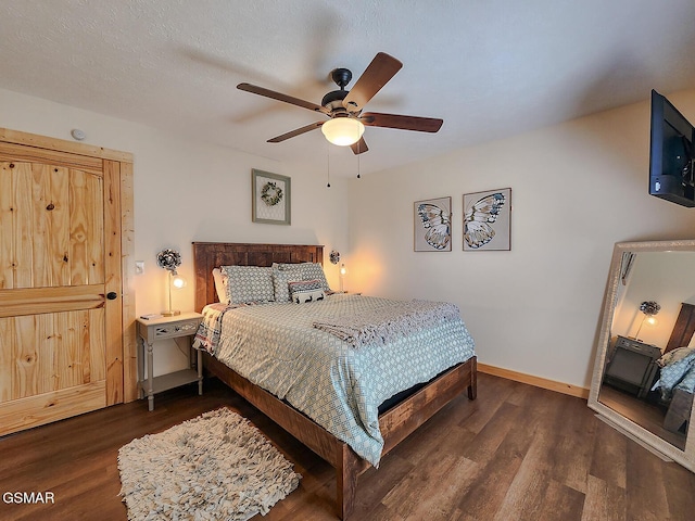 bedroom featuring a textured ceiling, a ceiling fan, dark wood-type flooring, and baseboards