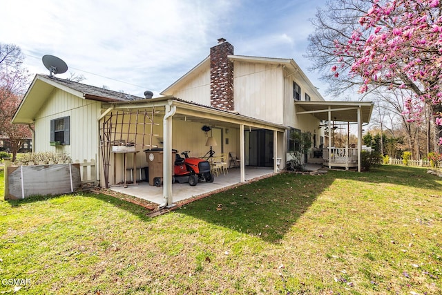 rear view of house with a patio area, a lawn, and a chimney