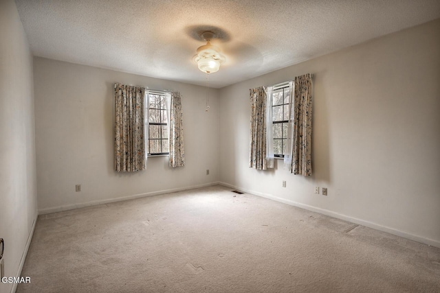 empty room with baseboards, visible vents, a textured ceiling, and carpet