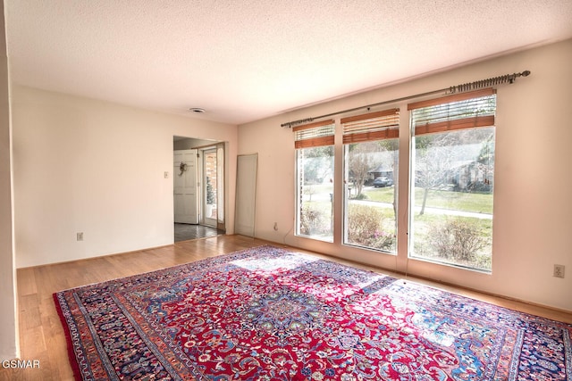 empty room with wood finished floors and a textured ceiling