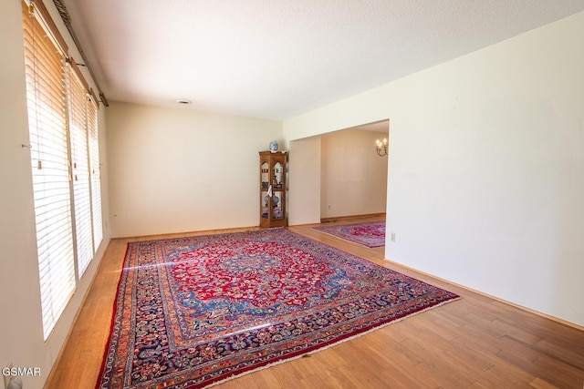 empty room featuring a textured ceiling, wood finished floors, and a chandelier