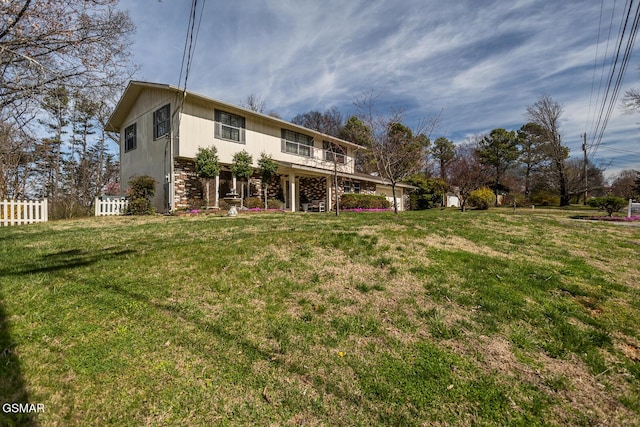 rear view of house with a lawn and fence