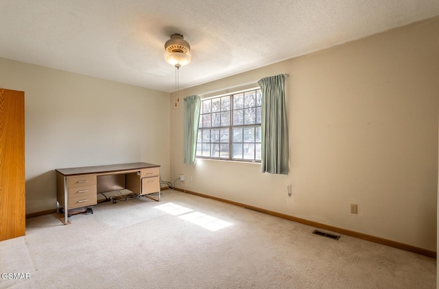 unfurnished office with light carpet, baseboards, visible vents, and a textured ceiling