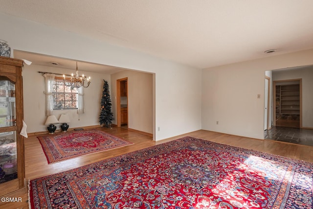 living area featuring a notable chandelier, wood finished floors, and baseboards