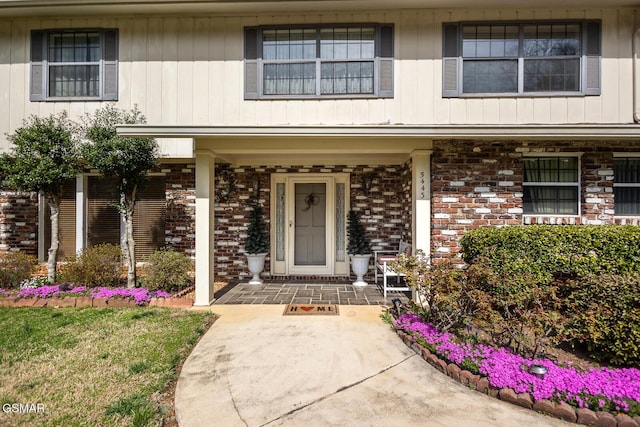 doorway to property featuring brick siding and a porch