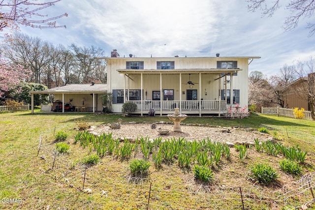 back of property with a lawn, ceiling fan, and fence