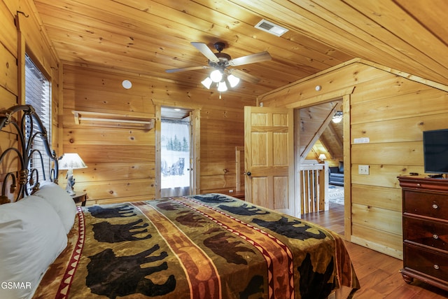 bedroom with wooden ceiling, visible vents, wood walls, and wood finished floors