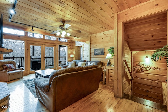 living area featuring french doors, light wood-style flooring, wood walls, ceiling fan, and wooden ceiling