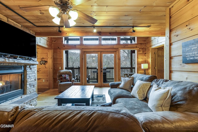 living room featuring french doors, wood walls, wooden ceiling, and wood finished floors