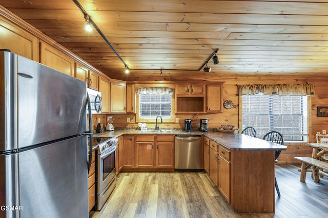 kitchen with stainless steel appliances, a peninsula, a sink, wood ceiling, and light wood-style floors