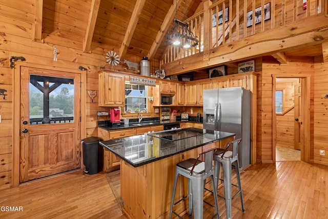 kitchen featuring beam ceiling, wooden ceiling, wooden walls, a kitchen island, and black appliances