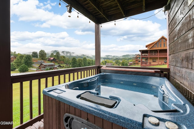 wooden deck featuring a mountain view, a yard, and a hot tub