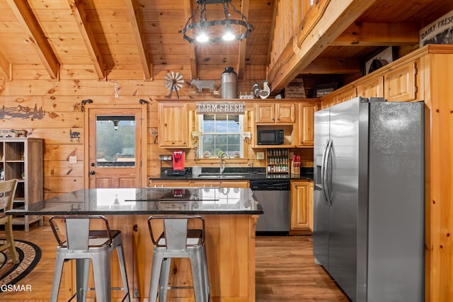 kitchen featuring wood walls, a center island, black appliances, and sink