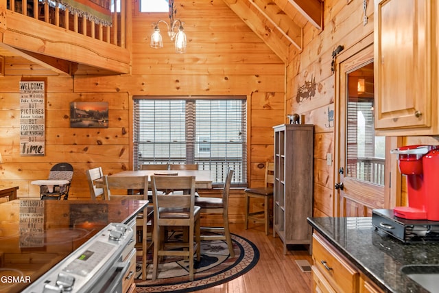 dining area featuring beamed ceiling, high vaulted ceiling, wood walls, light hardwood / wood-style floors, and wood ceiling