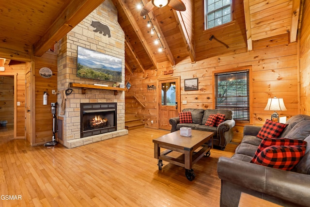 living room with track lighting, a fireplace, ceiling fan, wooden ceiling, and beamed ceiling