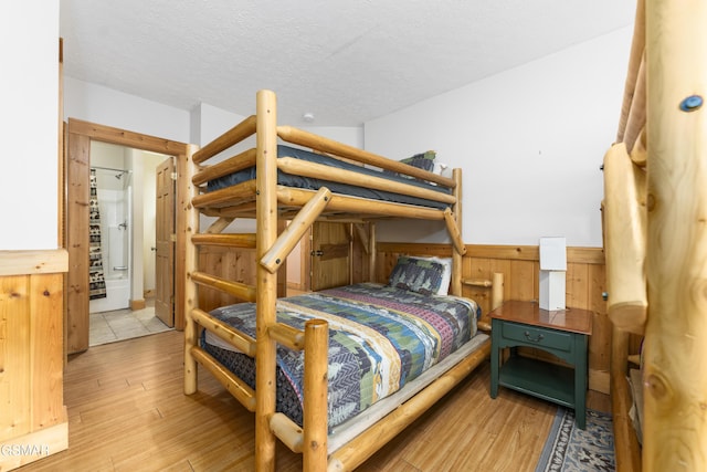 1251 Bear Cub Way, Gatlinburg, TN 37738 - bedroom featuring wood finished floors, a textured ceiling, wood walls, and wainscoting