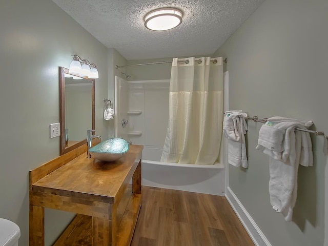 bathroom featuring toilet, shower / tub combo, wood finished floors, a textured ceiling, and vanity