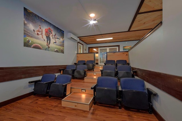 cinema room featuring wood finished floors, wainscoting, and a wall mounted AC