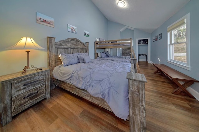 bedroom featuring lofted ceiling, wood finished floors, and baseboards