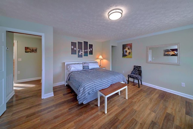 bedroom featuring a textured ceiling, baseboards, and wood finished floors