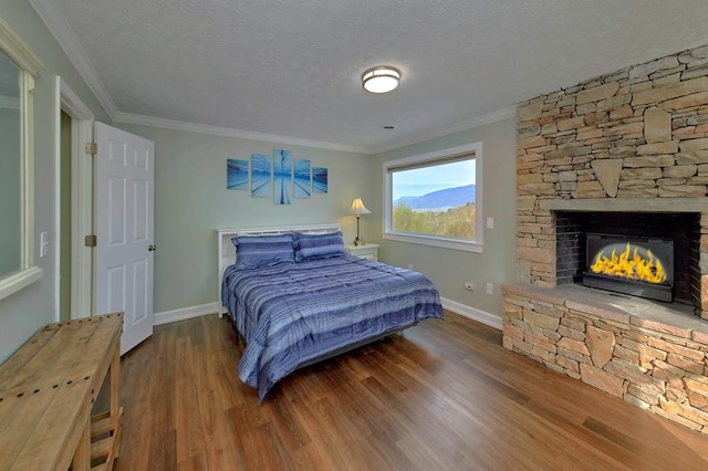 bedroom with ornamental molding, a fireplace, a textured ceiling, and wood finished floors