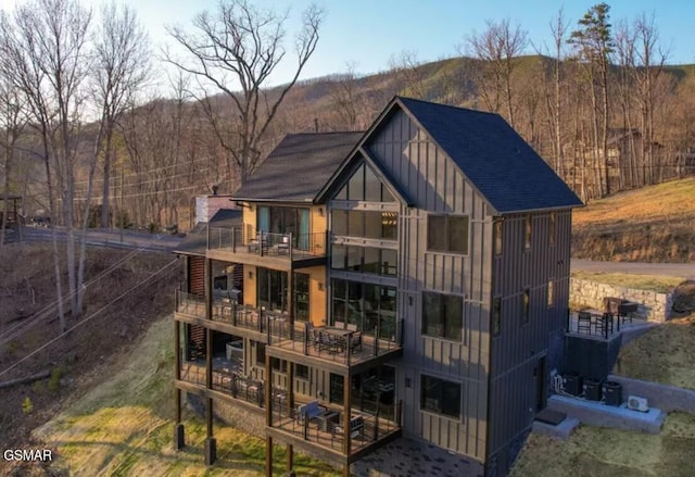 back of house featuring board and batten siding and a balcony