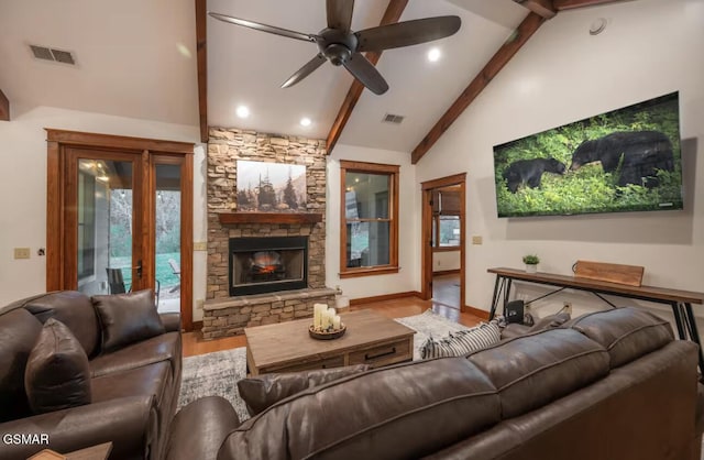 living room featuring a stone fireplace, high vaulted ceiling, ceiling fan, beam ceiling, and hardwood / wood-style floors