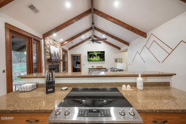 kitchen with ceiling fan, vaulted ceiling with beams, a fireplace, and stainless steel range with electric stovetop