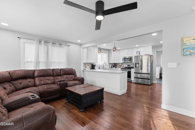 living room featuring dark hardwood / wood-style flooring, ceiling fan, and sink