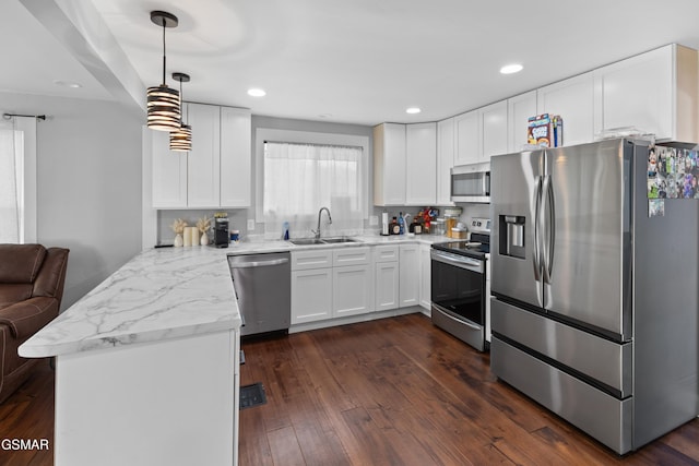 kitchen with sink, stainless steel appliances, kitchen peninsula, decorative light fixtures, and white cabinets