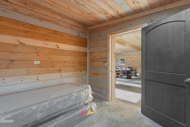 interior space featuring concrete flooring, wooden walls, and wood ceiling