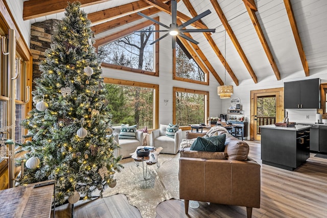 living room with light hardwood / wood-style floors, high vaulted ceiling, ceiling fan, and wooden walls