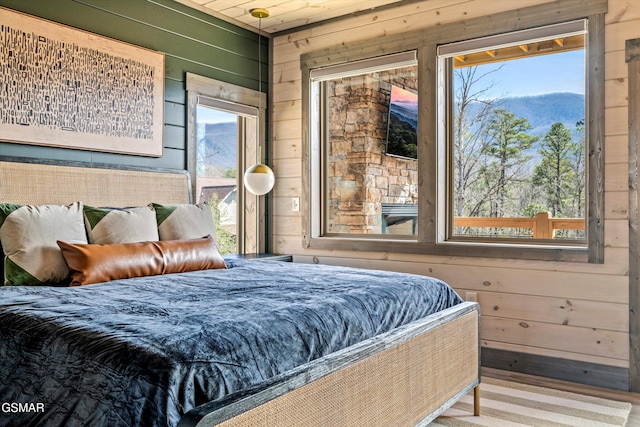 bedroom featuring access to outside, wooden walls, and multiple windows