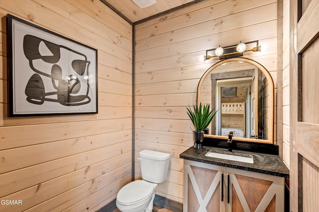 bathroom with wood walls, vanity, and toilet