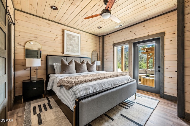 bedroom featuring wooden ceiling, wood walls, wood finished floors, visible vents, and access to exterior