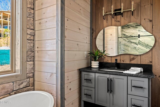 bathroom featuring wood walls, a freestanding bath, and vanity