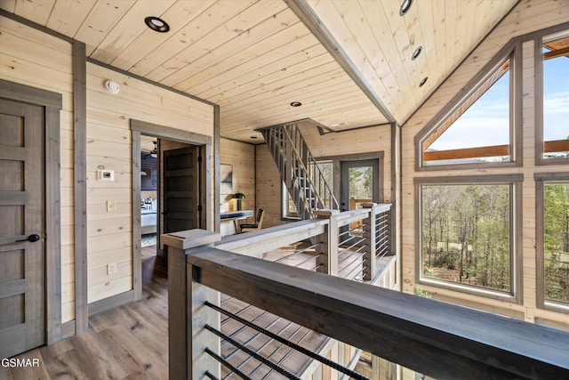 interior space featuring wooden ceiling, wooden walls, wood finished floors, an upstairs landing, and stairway