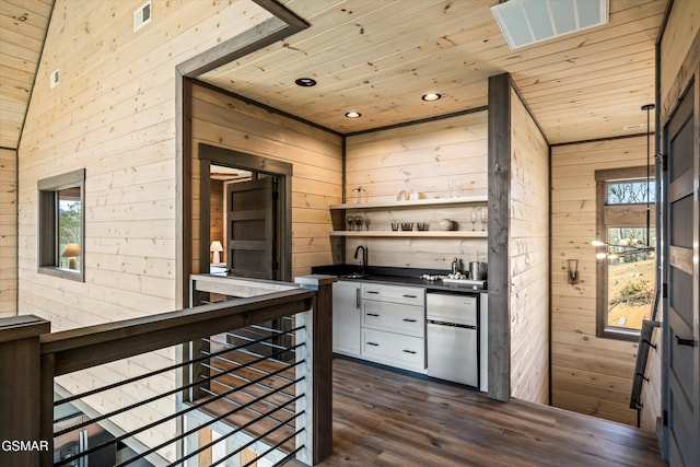 kitchen with plenty of natural light, wood walls, wood ceiling, and visible vents