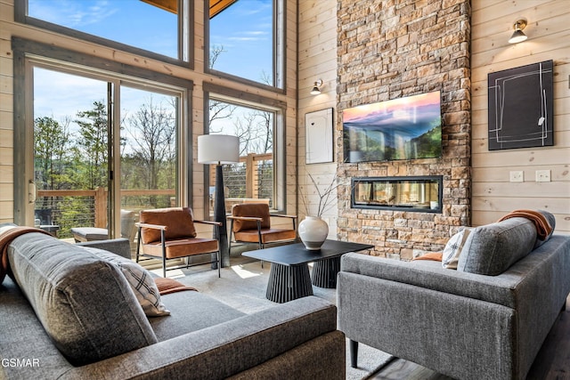 living area featuring a fireplace, a towering ceiling, and wooden walls