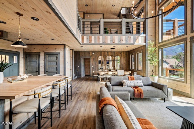 living area featuring wooden ceiling, wood walls, a towering ceiling, and an inviting chandelier