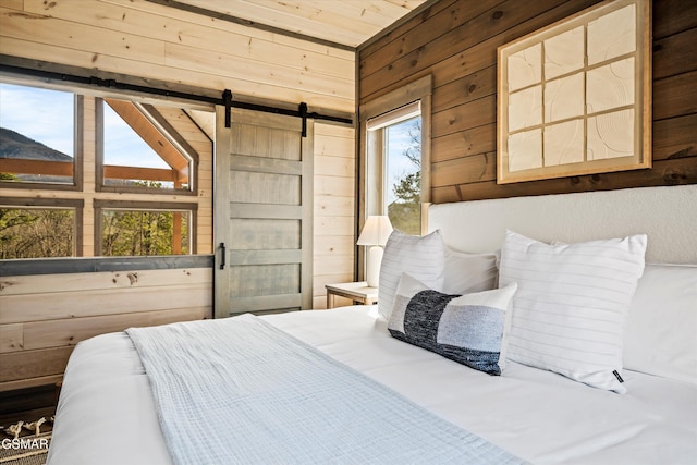 bedroom featuring a barn door and wooden walls