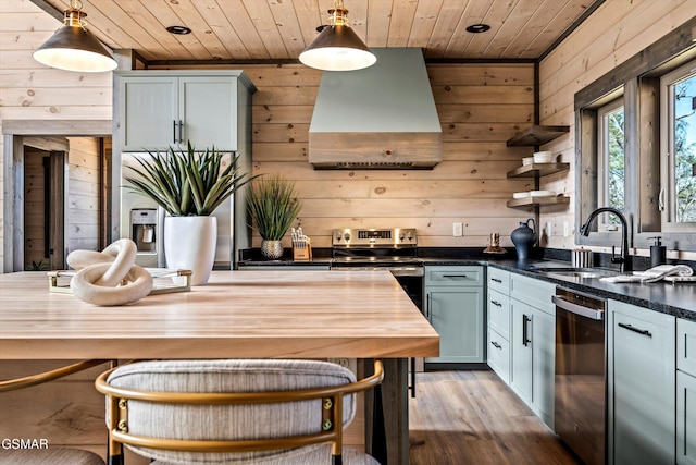 kitchen featuring stainless steel appliances, wall chimney range hood, a sink, and wood ceiling