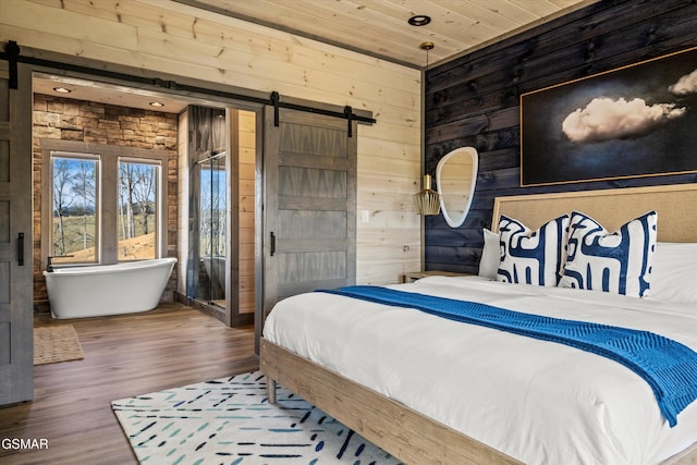 bedroom with wood ceiling, wood finished floors, wooden walls, and a barn door