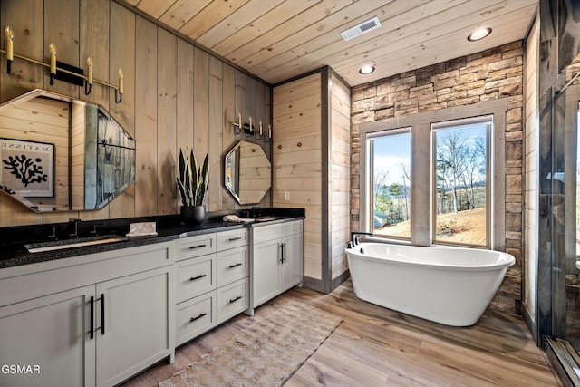 full bath featuring wooden ceiling, wooden walls, wood finished floors, visible vents, and double vanity