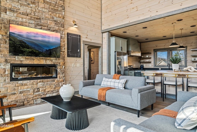 living area with wooden walls, an outdoor stone fireplace, and wood finished floors