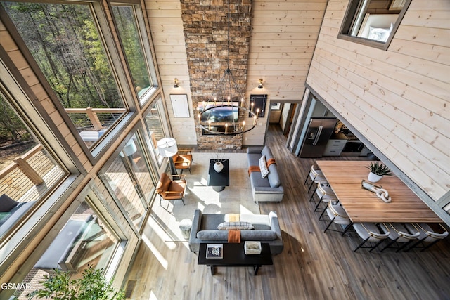 living room featuring a healthy amount of sunlight, wood finished floors, a high ceiling, and wooden walls