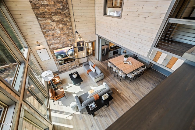 unfurnished living room with a towering ceiling, wood walls, wood finished floors, and an inviting chandelier