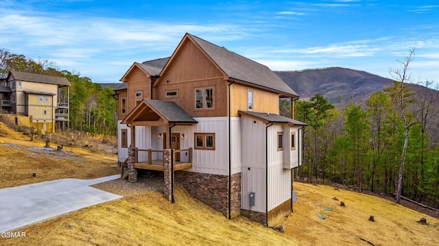 exterior space featuring stone siding, roof with shingles, and a mountain view