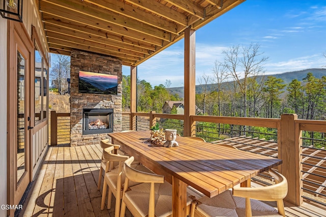 deck featuring an outdoor stone fireplace and outdoor dining area