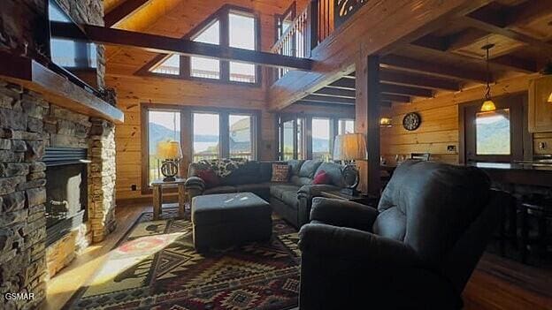 710 Village Loop Rd, Gatlinburg, TN 37738 - living room with wooden walls, beam ceiling, a fireplace, a towering ceiling, and wood finished floors